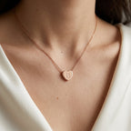 Collier doré à petit cœur gravé d'une initiale, porté au cou