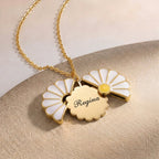 Gros plan sur un collier marguerite doré ouvert sur un prénom gravé
