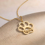 Gros plan sur un collier patte d'animal doré, prénom gravé à l'intérieur