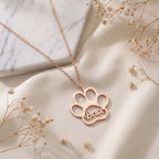 Collier patte d'animal en or rose posé à plat, prénom gravé