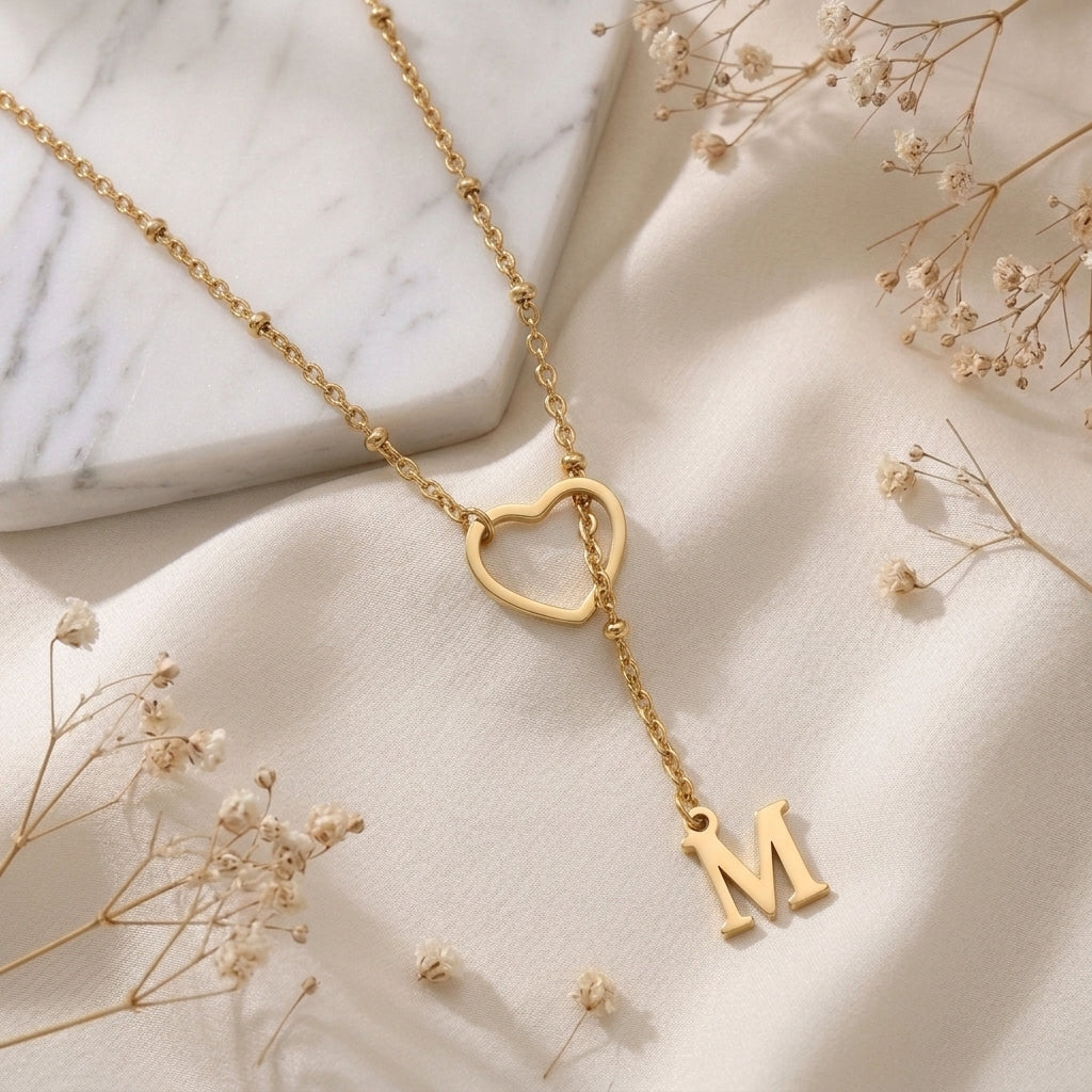 Collier doré à cœur ajouré et initiale gravée, posé à plat