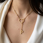 Collier doré à cœur ajouré et initiale porté au cou