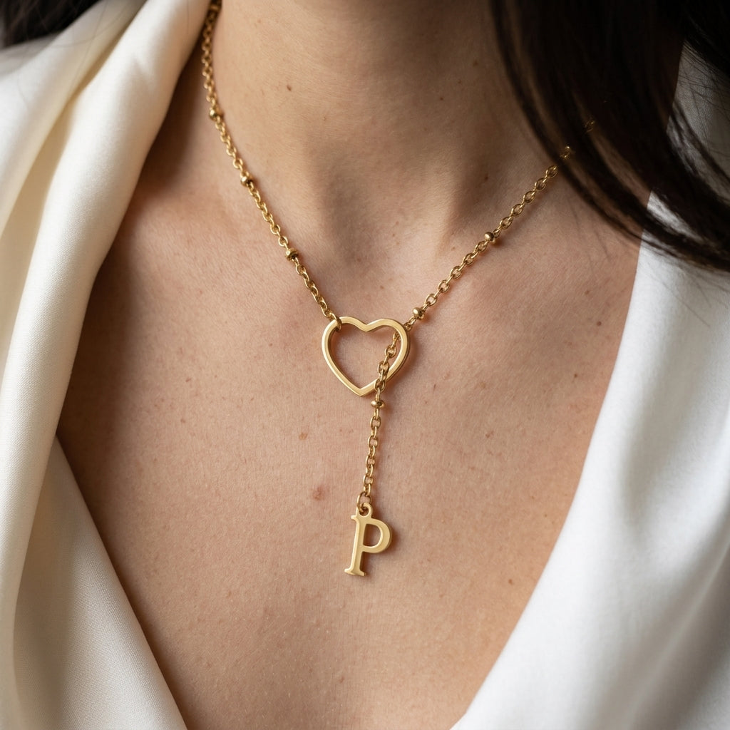 Collier doré à cœur ajouré et initiale porté au cou