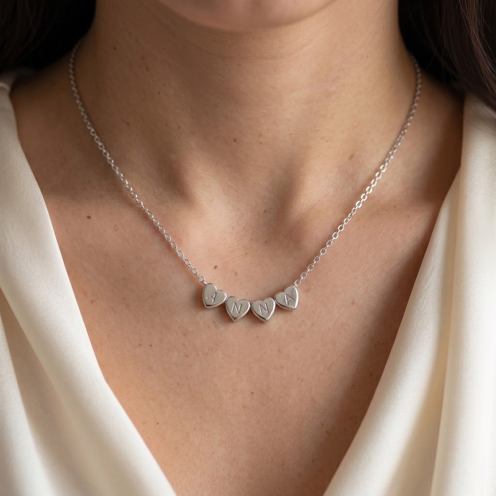 Collier en acier inoxydable à cœurs gravés d'initiales porté au cou