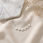 Collier en acier inoxydable à cœurs gravés d'initiales posé à plat