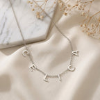 Collier en acier inoxydable à lettres majuscules formant un prénom, posé à plat