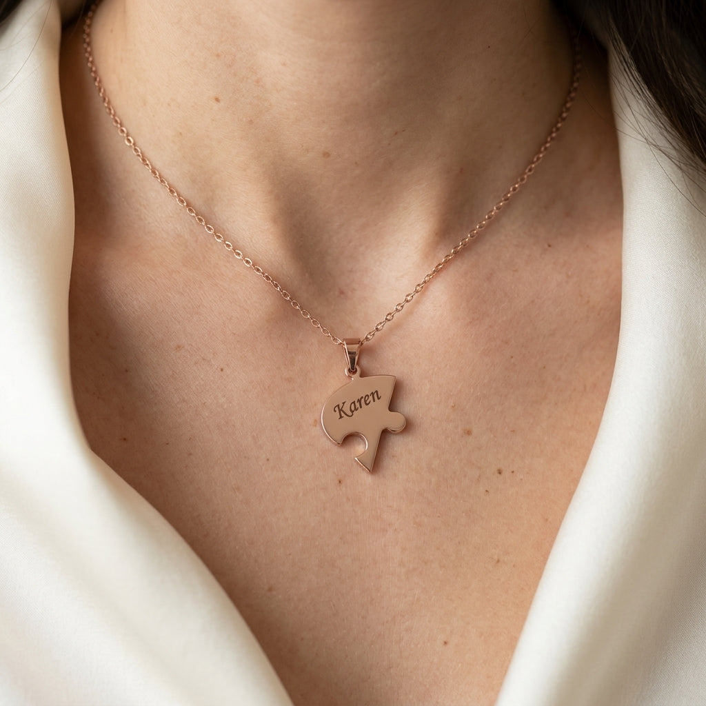 Pendentif puzzle en or rose porté au cou, un prénom gravé