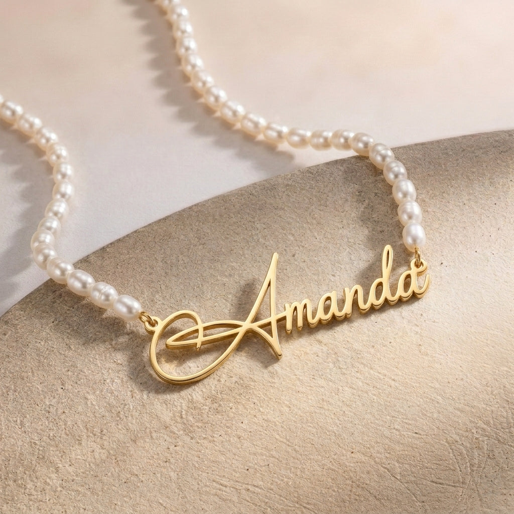 Collier de perles avec prénom doré en écriture manuscrite, vu de près