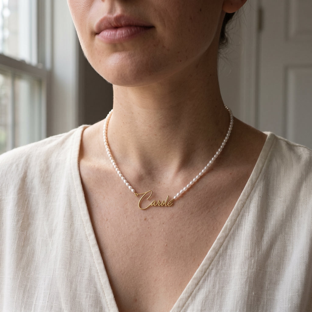 Collier de perles porté au cou, prénom doré en écriture manuscrite