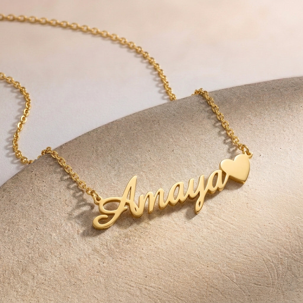 Gros plan sur un collier prénom doré terminé par un petit cœur