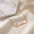 Collier prénom en or rose terminé par un cœur, posé à plat