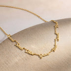 Gros plan sur un collier doré portant plusieurs prénoms sur une même chaîne