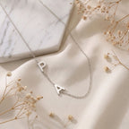 Collier en acier inoxydable aux lettres suspendues posé à plat