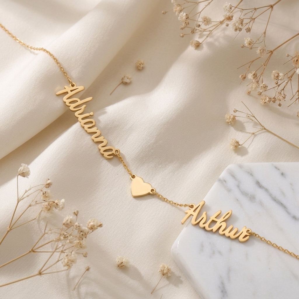 Collier doré à deux prénoms manuscrits et un cœur, posé à plat