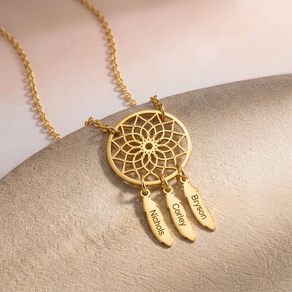 Gros plan sur un collier attrape-rêves doré, plumes gravées de prénoms