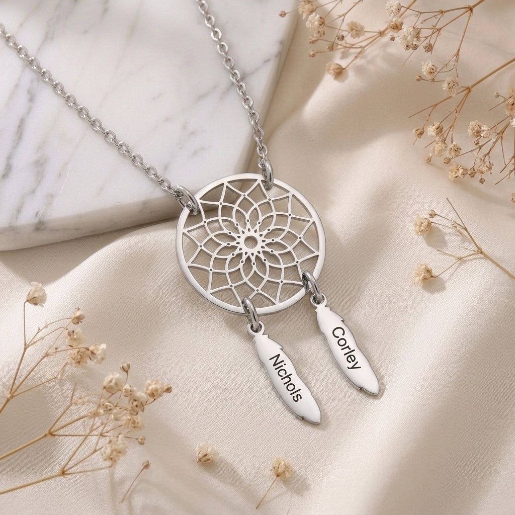 Collier attrape-rêves en acier inoxydable posé à plat, deux plumes gravées